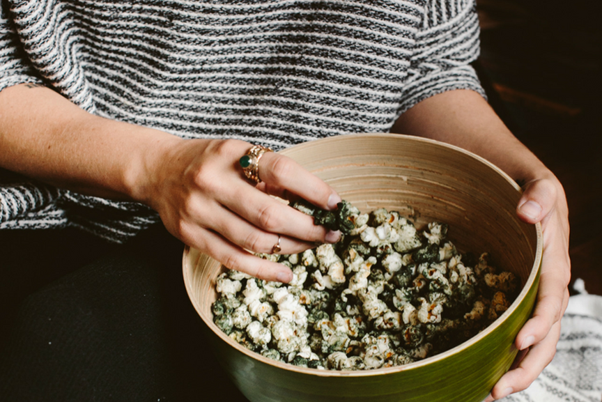 Woman holding bowl of Spirulina dusted popcorn