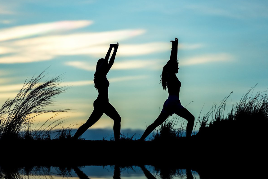 Two women doing yoga outdoors.